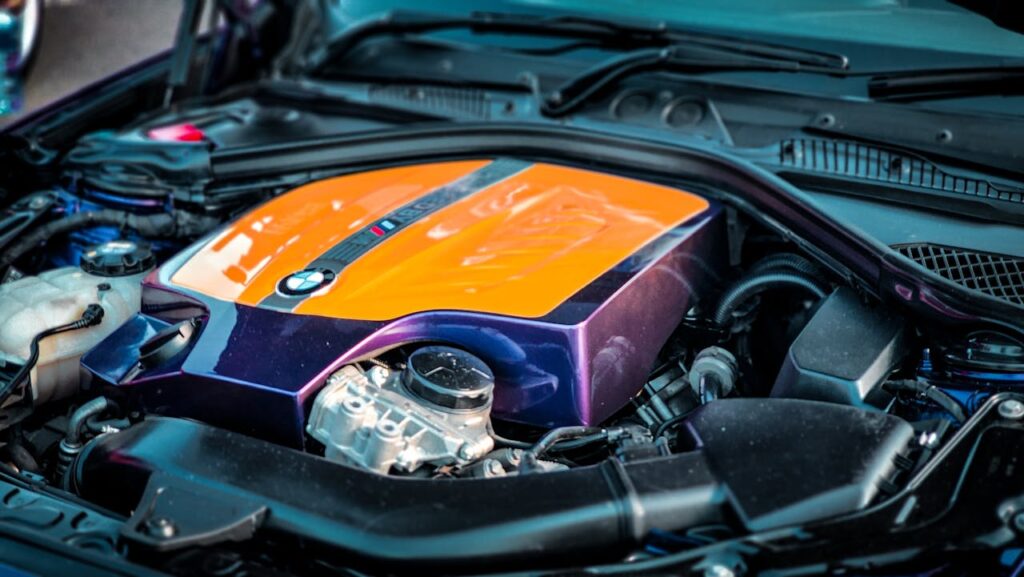 A detailed close-up view of a vibrant BMW engine under an open hood, showcasing its colorful design.