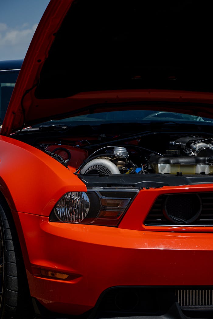 Detailed view of a red Ford Mustang with hood open showing engine components.
