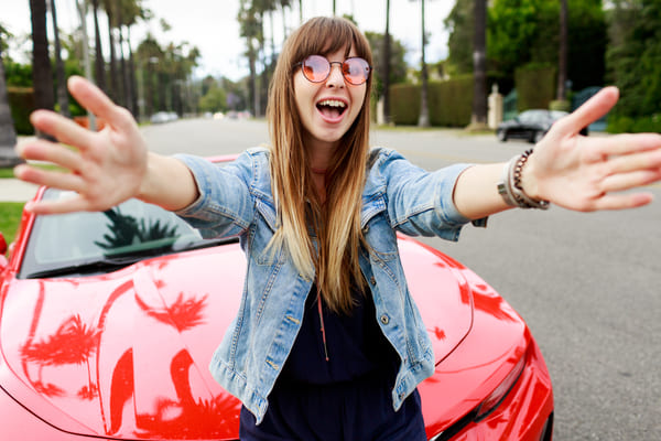 cute happy woman pink glasses making self portrait near amazing red convertible sport car california